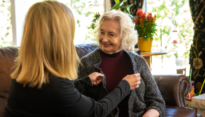 Family Caregiver supporting elderly aging parent with dressing